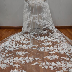 May include: White tulle fabric with floral embroidery and sequins. The fabric has a delicate, sheer texture and is adorned with intricate floral patterns. The sequins add a touch of sparkle and shimmer to the fabric. The fabric is ideal for creating wedding veils, bridal gowns, and other special occasion garments. SIZE USA is written on the fabric.