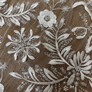 May include: White floral lace fabric with pearl and sequin embellishments.