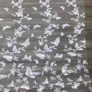 Pu&ograve; includere: Tessuto di pizzo bianco con un delicato motivo a farfalla. Le farfalle sono ricamate su uno sfondo di rete trasparente.