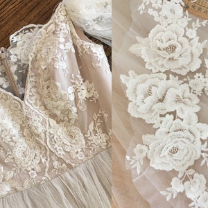 Puede incluir: Un vestido de encaje blanco con escote en V y bordados florales. El vestido tiene una superposici&oacute;n transparente y un delicado patr&oacute;n floral.