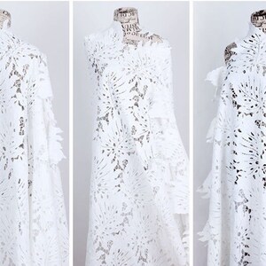 May include: White lace fabric with a floral pattern. The fabric is delicate and has a soft texture.