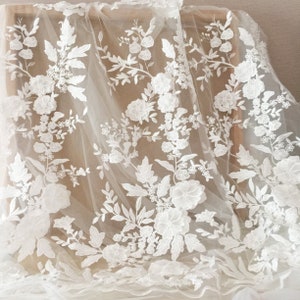 May include: White floral lace fabric with a delicate pattern of flowers and leaves. The lace is on a sheer, ivory background.