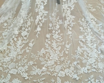 Tecido de renda de luxo em marfim com bordado floral de lantejoulas e miçangas, ideal para vestidos de noiva. Renda de alta costura vendida por metro.