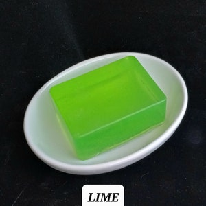 May include: A bright green bar of soap in a white dish. The soap is translucent and has a slight shimmer. The text "LIME" is printed below the dish.