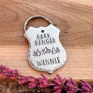 May include: Silver dog tag with a mountain scene and the text "Bark Ranger" and "Winnie".