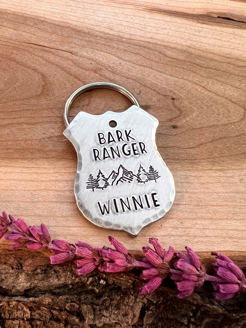 May include: Silver dog tag with a mountain scene and the text "Bark Ranger" and "Winnie".