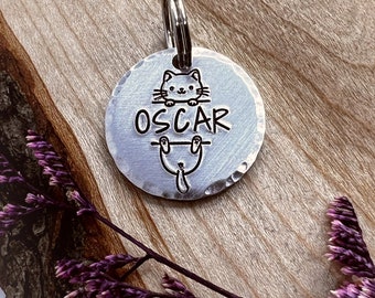 May include: Silver cat-shaped pet ID tag with the name "OSCAR" engraved on it.