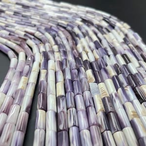 May include: A strand of purple and white shell beads, each bead is a cylinder shape with a smooth, polished finish.