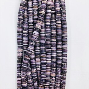 May include: A strand of purple and white shell beads. The beads are flat and round, and they are stacked on top of each other.