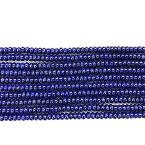 May include: Close-up of multiple strands of deep blue lapis lazuli beads. The beads are small, round, and evenly sized, creating a consistent texture. The color is a rich, saturated blue, with a slight sheen. Ideal for jewelry making.