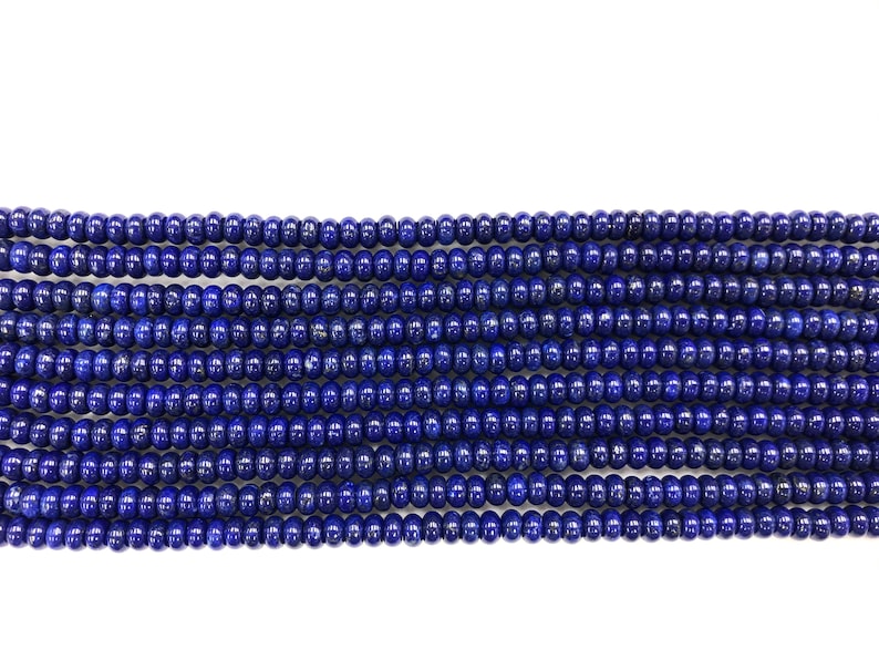 May include: Close-up of multiple strands of deep blue lapis lazuli beads. The beads are small, round, and evenly sized, creating a consistent texture. The color is a rich, saturated blue, with a slight sheen. Ideal for jewelry making.