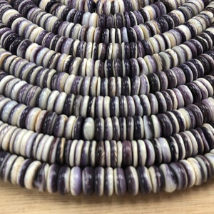 May include: A strand of purple and white shell beads. The beads are round and have a smooth, polished finish.