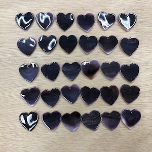 May include: Thirty-six purple heart-shaped shell pendants with a natural, iridescent finish.