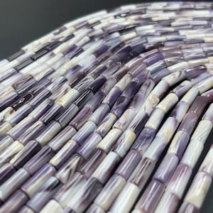May include: A strand of purple and white shell beads, each bead is a cylinder shape.