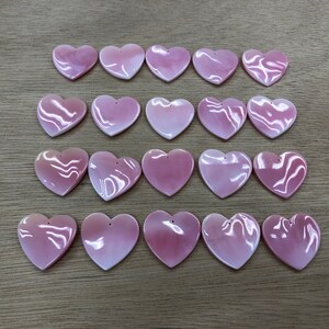 May include: Twenty pink heart-shaped shell charms with a hole at the top for stringing or attaching to jewelry.