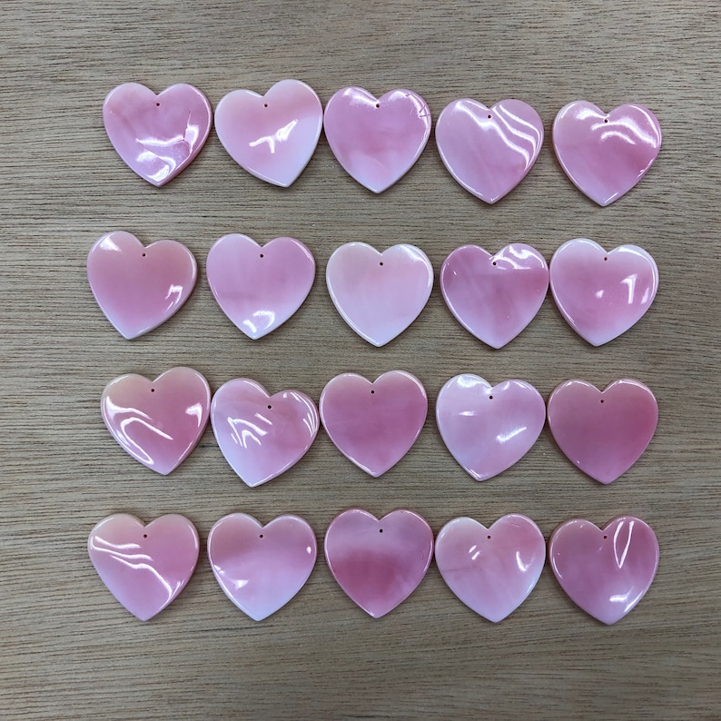 May include: Twenty pink heart-shaped shell charms with a hole at the top for stringing or attaching to jewelry.
