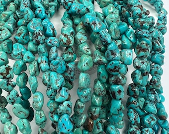 May include: A strand of turquoise gemstone beads, each bead is a unique, irregular shape with a mottled blue and brown colour.