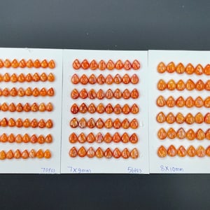 May include: Three rows of orange teardrop-shaped cabochons, each row with a different size: 6x8mm, 7x9mm, and 8x10mm. The cabochons are arranged in a grid pattern on a white surface. The text "6x8mm", "7x9mm", "8x10mm", "70pcs", "56pcs", and "42pcs" is printed below each row.