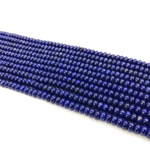 May include: Strands of small, round, deep blue beads. The beads have a polished, glossy finish and are strung together, creating a dense, textured surface. The beads are a consistent size and color, suggesting they are uniform in shape and material.