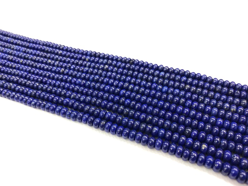 May include: Strands of small, round, deep blue beads. The beads have a polished, glossy finish and are strung together, creating a dense, textured surface. The beads are a consistent size and color, suggesting they are uniform in shape and material.