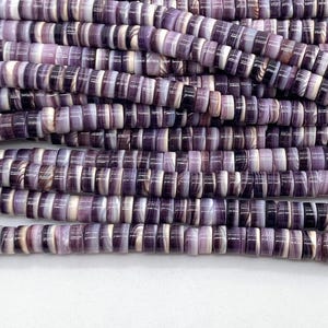 May include: Multiple strands of flat, circular disc beads arranged in parallel rows. The beads feature a marbled pattern with varying shades of deep purple, lavender, and white, creating a smooth, consistent texture across the entire collection.