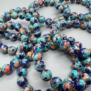 May include: Strands of beaded bracelets featuring round, colorful beads. The beads are a mix of turquoise, navy blue, and orange, creating a vibrant and eye-catching design. The bracelets are likely for fashion or jewelry.