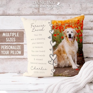 May include: Cream-colored pillow with a photo of a golden retriever and red flowers. Text on the pillow reads "Forever Loved" and includes a memorial message and the name "Charlie" with dates. The pillow is on a white wooden surface.