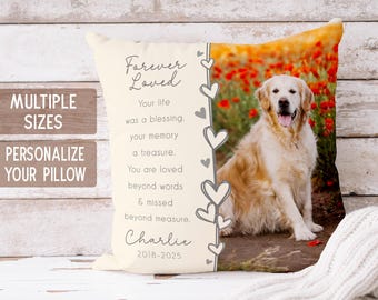 May include: Cream-colored pillow with a photo of a golden retriever and red flowers. Text on the pillow reads "Forever Loved" and includes a memorial message and the name "Charlie" with dates. The pillow is on a white wooden surface.