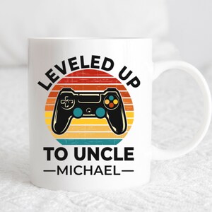 May include: White ceramic mug with a retro-style graphic of a video game controller and the text "LEVELED UP TO UNCLE -MICHAEL-"