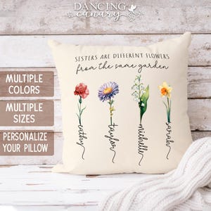May include: Cream-colored pillow with the text "Sisters are different flowers from the same garden." Features four watercolor flowers with names: Cathy, Taylor, Michelle, and Sarah. The pillow has a soft, inviting appearance.