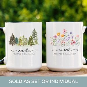 May include: Two white ceramic mugs with black handles. One mug features a watercolor illustration of a forest with the text "uncle Michael & Samantha". The other mug features a watercolor illustration of flowers with the text "aunt Michael & Samantha".
