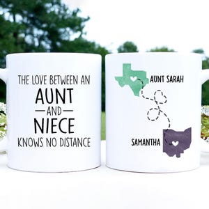 May include: Two white coffee mugs with black text. The mug on the left says "The love between an aunt and niece knows no distance". The mug on the right has a map of Texas and Ohio with the names "Aunt Sarah" and "Samantha" and a heart in each state.