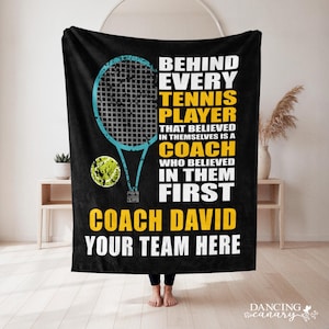 May include: A black fleece blanket featuring a blue tennis racket graphic, a yellow tennis ball, and white and yellow text that reads: BEHIND EVERY TENNIS PLAYER THAT BELIEVED IN THEMSELVES IS A COACH WHO BELIEVED IN THEM FIRST COACH DAVID YOUR TEAM HERE.