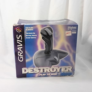 May include: A Gravis Destroyer PC joystick in its original cardboard packaging. The box features a purple and yellow lightning graphic, the text "Easy-to-use PC joystick," "Two rapid-fire buttons, smooth action throttle," and "Windows 95 and 98 compatible."