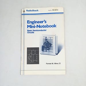 May include: A white RadioShack Engineer's Mini-Notebook titled Basic Semiconductor Circuits by Forrest M. Mims III, Cat. No. 62-5013. The cover features a blue title, a black and white circuit diagram, and a photograph of a breadboard circuit.
