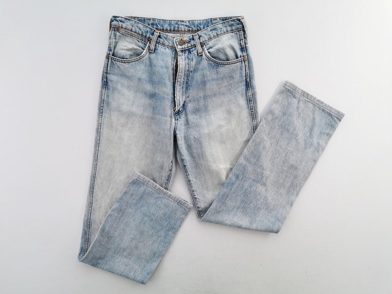 May include: Light blue denim jeans with a faded wash. The jeans have a classic five-pocket design, a button and zipper closure, and a straight leg. The garment is made of cotton and is a size 32 x 30.