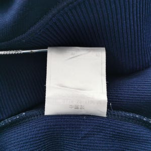 May include: A white ceramic mug with a black handle and the text "But First, Coffee" in a black, bold font. The mug is on a white surface.