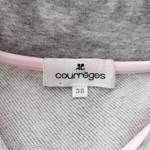 May include: Close-up of a gray sweatshirt collar with a pink trim. A white label displays the brand name "courr&egrave;ges" and the size "38". The fabric has a textured appearance.