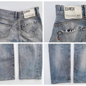 May include: Light blue denim jeans with distressed details. The jeans feature a classic five-pocket design, a faded wash, and a leather patch with the brand name "EDWIN". The back pockets have a unique stitching pattern. The jeans are a size XU-S.
