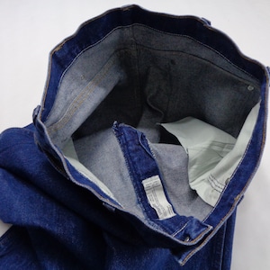 May include: Close-up of a pair of blue denim jeans. The jeans are unbuttoned and unzipped, revealing the interior pockets and waistband. The denim is a deep indigo color, with visible stitching and a light-colored interior.