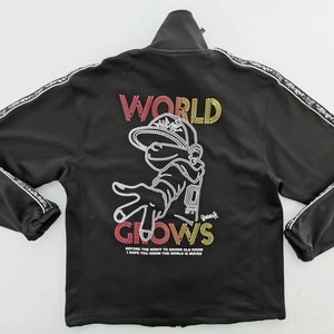 May include: Black zip-up jacket with white trim and a graphic on the back. The graphic features the words "WORLD GROWS" and a cartoon character. The jacket has a high collar and long sleeves.