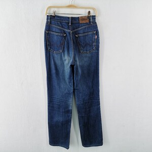 May include: Dark wash denim jeans hanging on a wooden hanger. The jeans have a high waist, straight leg, and classic five-pocket design. A brown leather patch with the brand name is visible at the back.