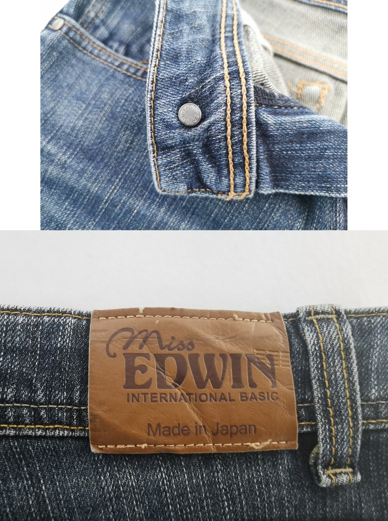 K&ouml;nnte beinhalten: Blaue Jeans aus Denim mit einem Metallknopf, der mit dem Wort EDWIN gepr&auml;gt ist. Ein brauner Lederaufn&auml;her am Bund zeigt den Text Miss EDWIN INTERNATIONAL BASIC und Made in Japan, vern&auml;ht mit kontrastierendem goldfarbenem Garn.