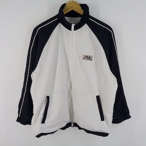 May include: A white and navy blue track jacket with a full zipper closure. The jacket features a high collar, side pockets, and the "FILA" logo on the chest. White piping accents the navy blue sleeves.