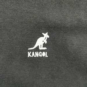 May include: Black fabric with a white embroidered kangaroo logo and the brand name "KANGOL" below it. The logo is a stylized kangaroo holding a cane. The fabric appears to be a t-shirt or other apparel item.