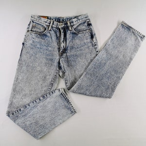 K&ouml;nnte beinhalten: Jeans aus Acid-Wash-Denim mit einem hellblauen und wei&szlig;en Muster. Die Jeans haben ein klassisches F&uuml;nf-Taschen-Design und ein gerades Bein. Die Jeans liegen flach auf einer wei&szlig;en Oberfl&auml;che.
