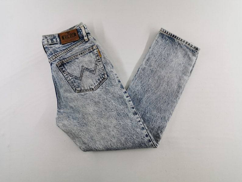K&ouml;nnte beinhalten: Jeans aus Acid-Wash-Denim mit klassischem F&uuml;nf-Taschen-Design. Die Jeans haben ein hellblaues und wei&szlig;es Marmormuster, einen braunen Lederaufn&auml;her mit dem Markennamen "Edwin" und eine Ges&auml;&szlig;tasche mit einer markanten "W"-Naht.