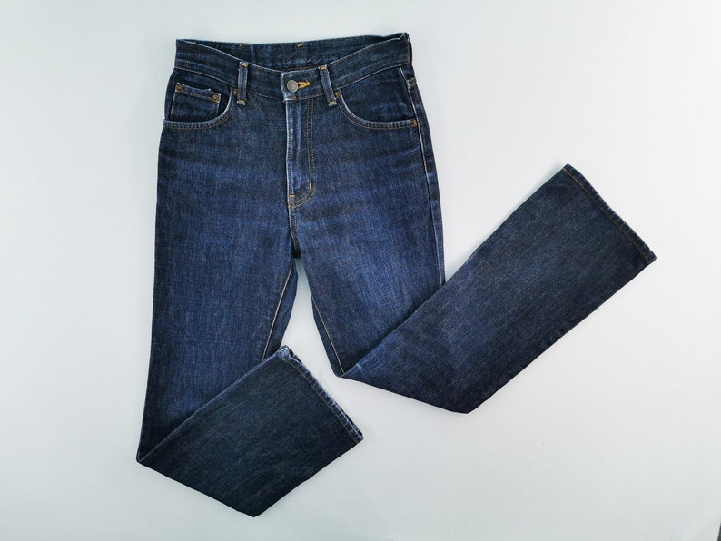 May include: Dark wash denim jeans with a classic five-pocket design. The jeans have a straight leg cut and a button and zipper closure. The jeans are made of a sturdy denim material and are suitable for everyday wear.