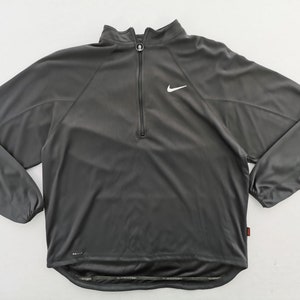 Pu&ograve; includere: Top sportivo grigio antracite con zip a un quarto e logo Nike bianco. Il top a maniche lunghe ha un collo alto ed &egrave; realizzato in materiale leggero e traspirante. La scritta "DRI-FIT" &egrave; stampata in basso a sinistra.