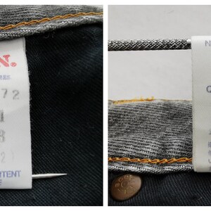 May include: Close-up of two white tags attached to a pair of denim jeans. One tag features the brand name "EDWIN" in red, with size and care information. The other tag displays washing instructions and fabric content.